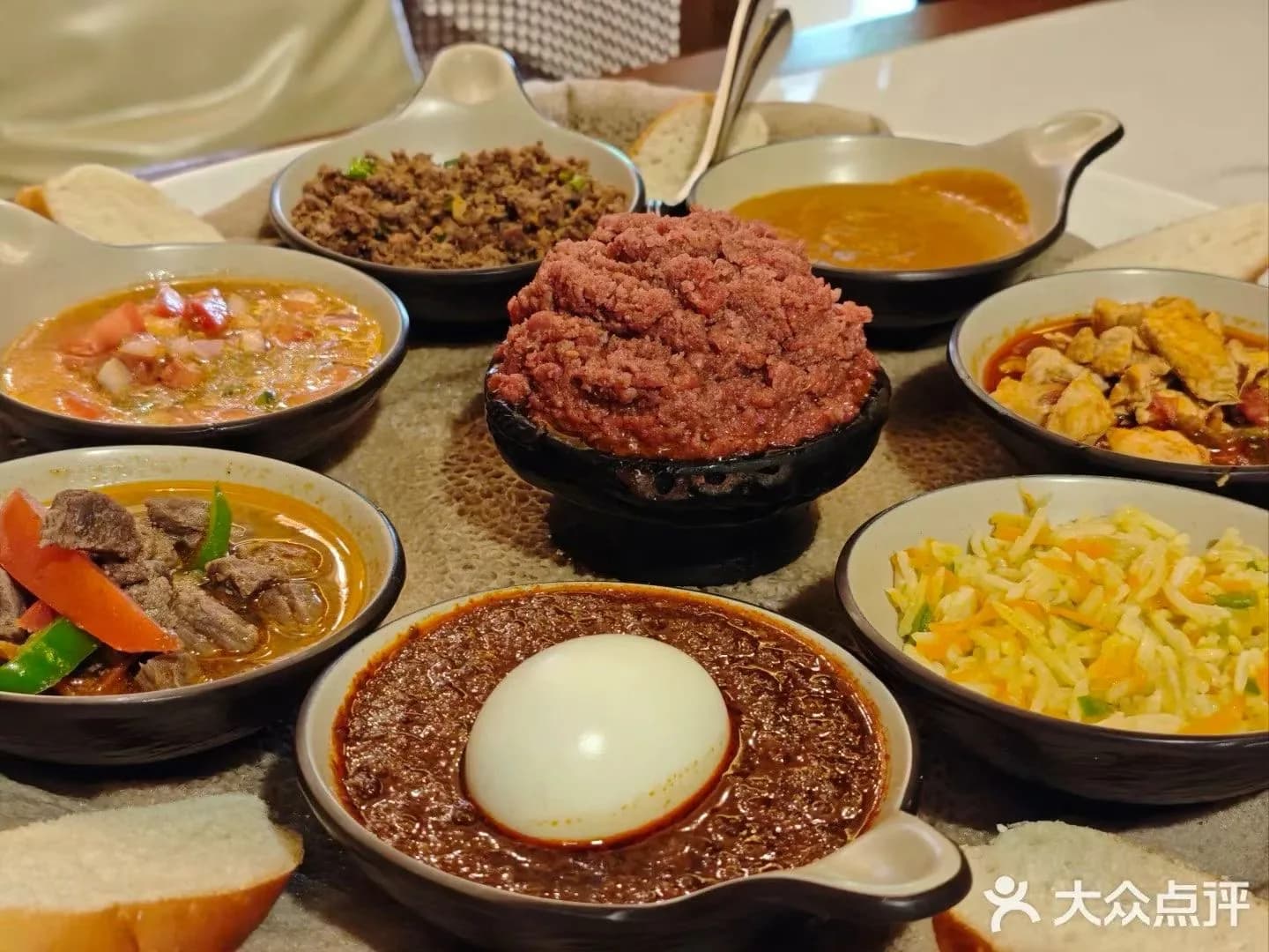 A close table-level view of Ethiopian dishes, with an egg-topped red stew in the foreground.